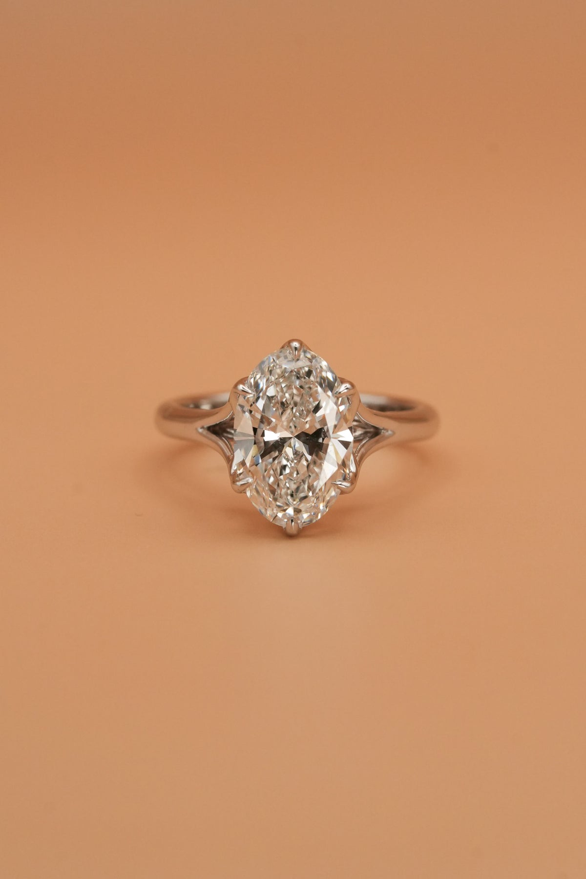 Face-up view of an oval diamond solitaire ring with split shank in 18K white gold